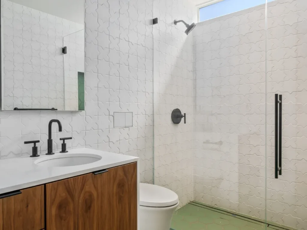 Minimalistic bathroom with white tiles and wood accents.
