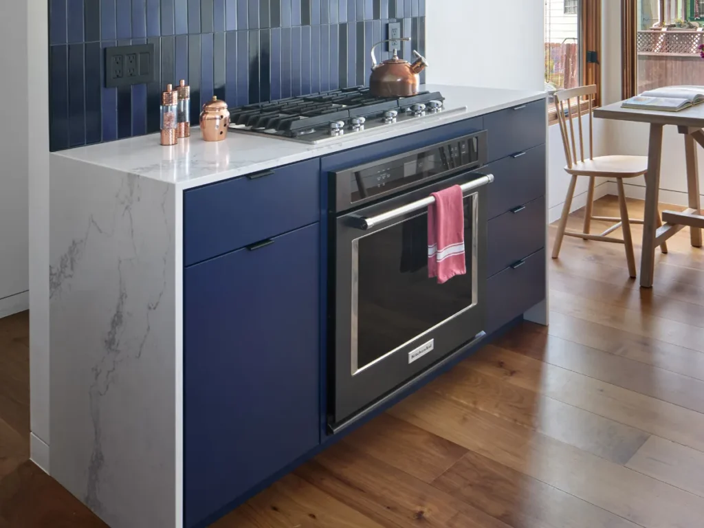 Modern kitchen with navy cabinetry and marble.