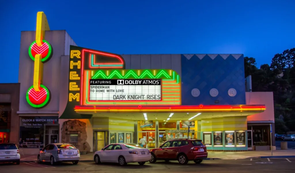 Colorful cinema marquee with cars parked outside.