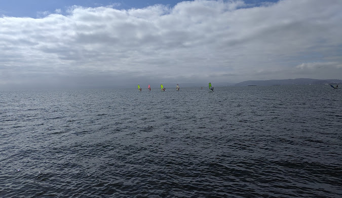Foggy ocean view with small sailboats.