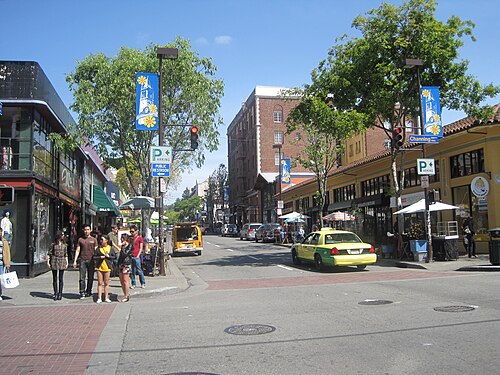 Busy city street with trees and storefronts.