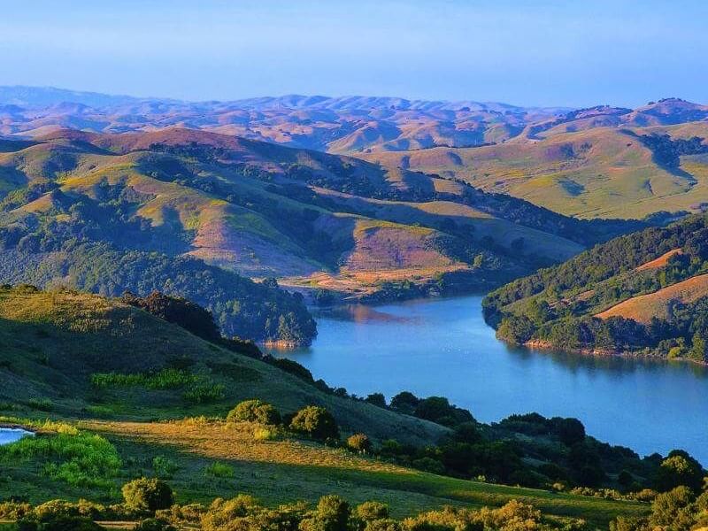 Scenic landscape with green hills and a calm lake.