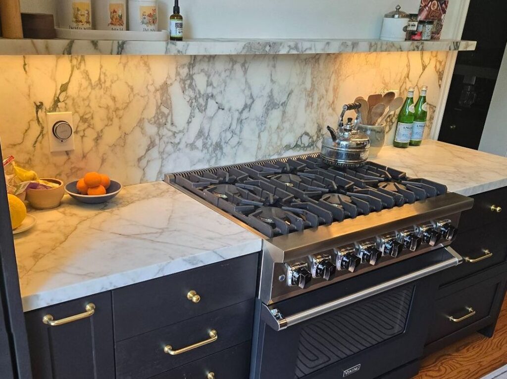 Close-up of stove, marble backsplash, blue cabinets