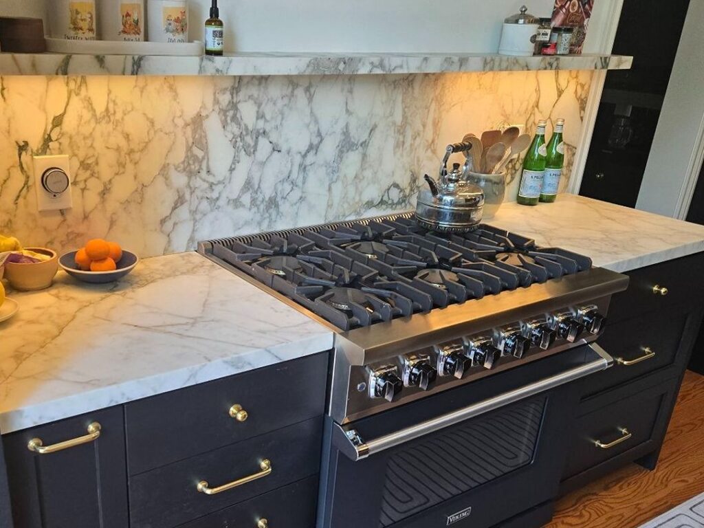 Elegant kitchen with marble backsplash and stovetop.