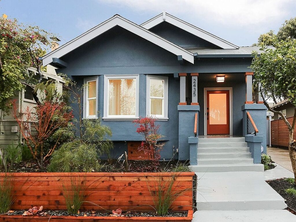Small blue home exterior with red door.