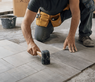 Contractor installing floor tiles during home renovation