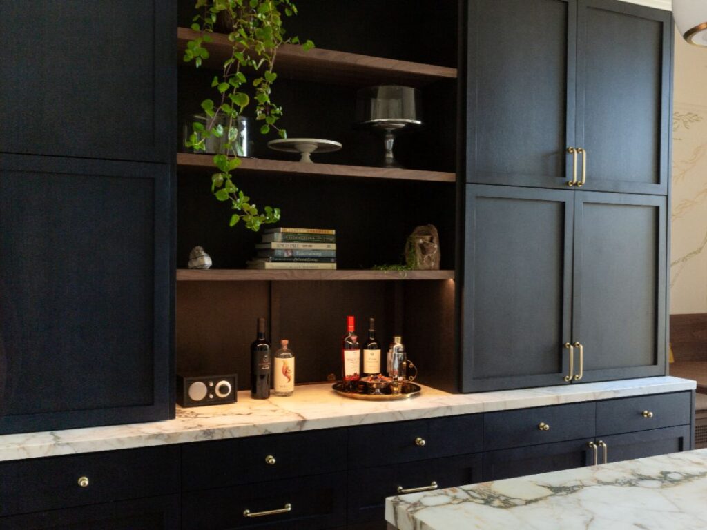Dark kitchen cabinets with marble counter and plants.