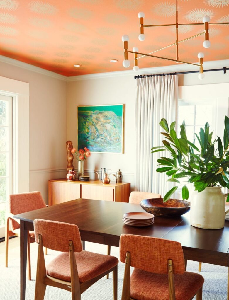 Dining room with orange ceiling and framed artwork.
